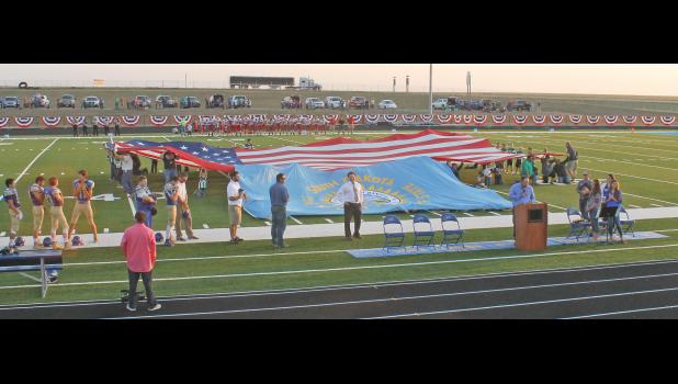 The dedication of the Wall School District’s outdoor athletic facility included volunteers holding up a huge American flag, as well as a slightly smaller South Dakota state flag.
