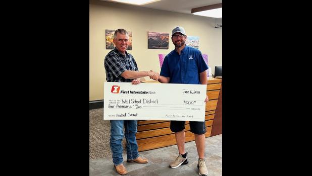 Brett Blasius, President of the First Interstate Greater Wall Fund presents a $4000 grant to Lex Heathershaw, head football coach with the Wall School District, for wireless headsets for the athletic department. Courtesy Photo