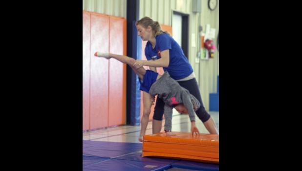 Abby shown guiding a student through a cartwheel.