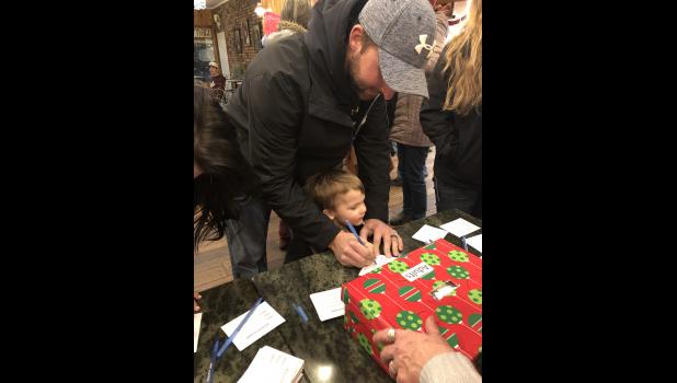 Tyrel Eisenbraun showing his son Landon how to sign up for the door pizes. Courtesy photo 2018 Pancake supper.