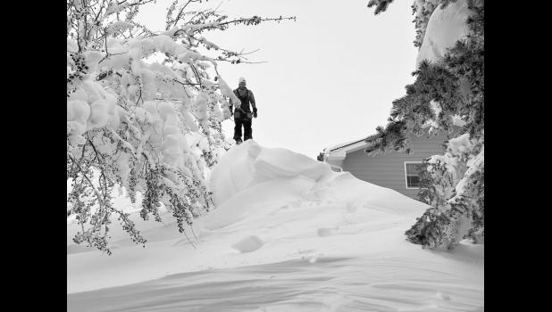 Matthew Birkeland stands on a drift as high as his house. Photo by Jeff Birkeland
