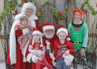 Santa, Mrs. Claus, an elf take time to pose with children.