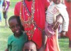 A young Maasai woman poses with her three children. Her husband would be considered well on his way to wealth, since wealth for the Maasai is measured in cattle and children.