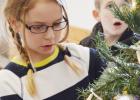 Malayne Condra, third grade, carefully places her ornament as her classmate, Tyler Cook, takes in the wonder of the class tree.